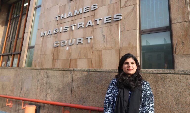 A volunteer courtwatcher stands in front of Thames Magistrates Court
